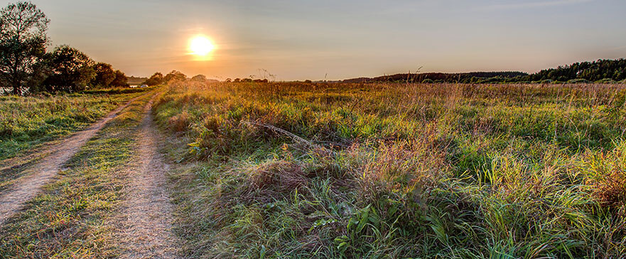 Summer sunset over field and road near bank of Volga River oppos
