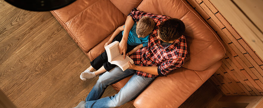 Father son relaxing at home on sofa reading a book, story, bible