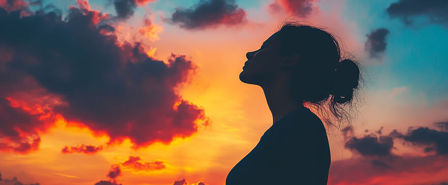 Silhouette of a woman sitting on the grass praying in front of a